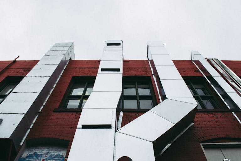 Low angle view of a modern industrial facade with prominent metal ducts on a red brick building.