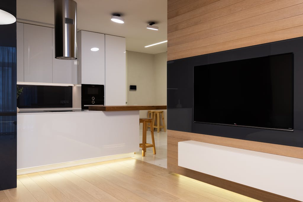 Spacious and stylish modern kitchen and living room interior with wooden and glossy finishes.